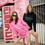 womens pink and black zipper hoodie with white komera neza print logo
