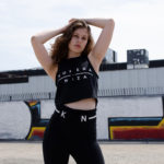 woman in black yoga set with white komera neza print logo