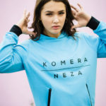 woman wearing neon blue zipper hoodie with black komera neza print logo