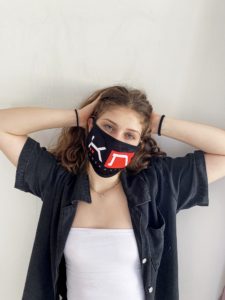 Woman wearing black face mask with KOMERA NEZA logo